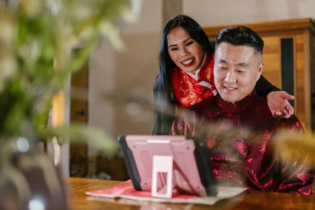 Asian couple in traditional clothing using a digital tablet indoors for communication.