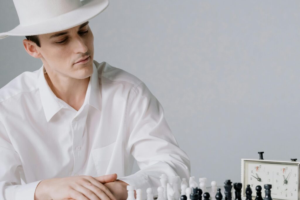 Man in a white hat thoughtfully contemplating a chess game. Strategic thinking captured.
